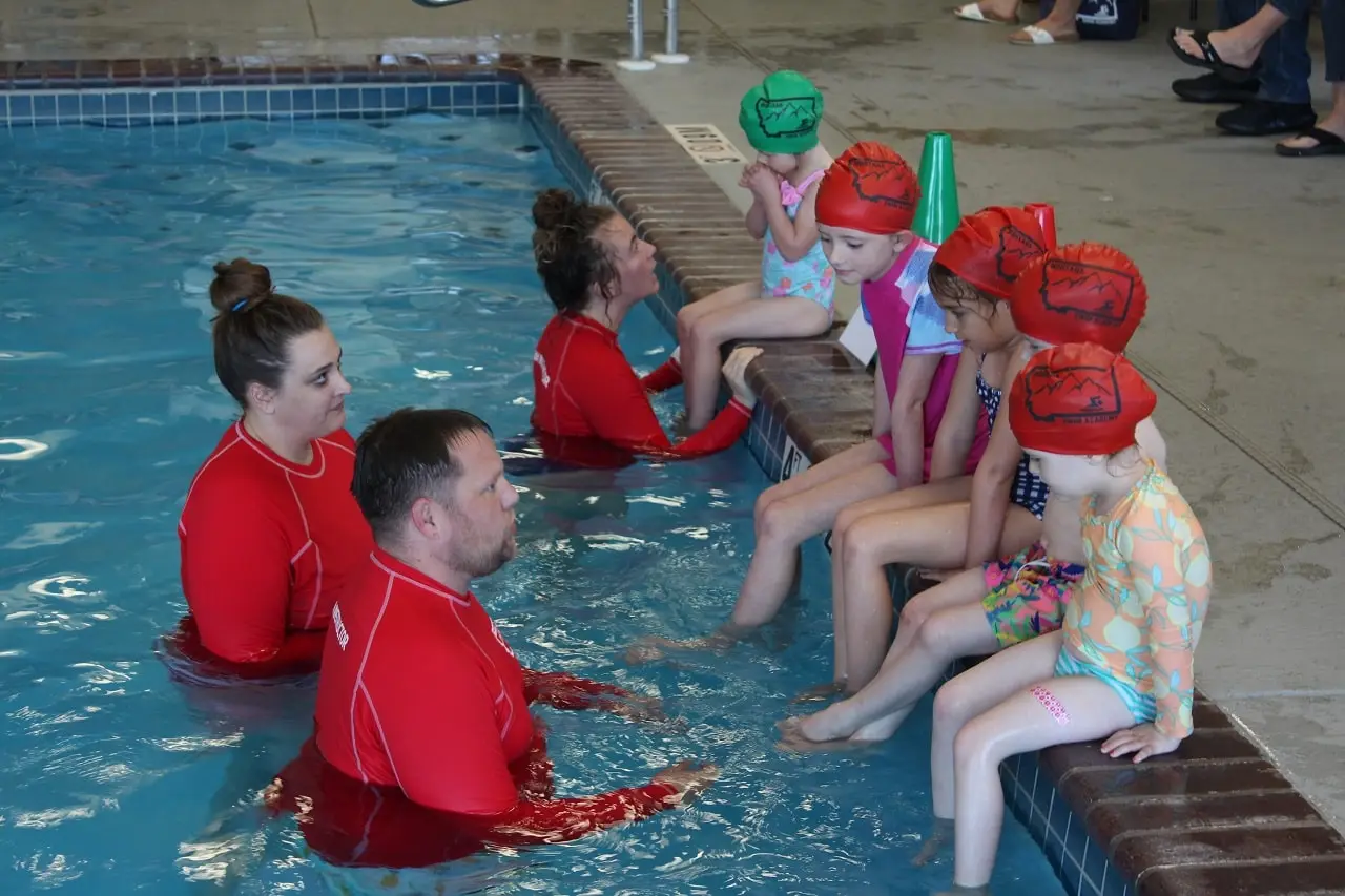 Montana Swim Academy Instructors talk with students who sit poolside.