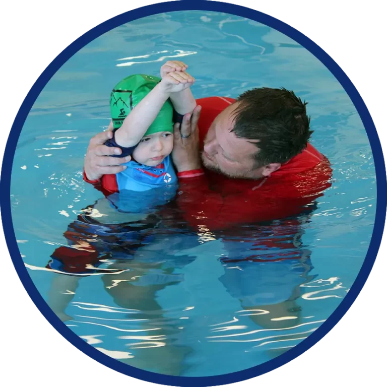 swimming instructor helping young boy with arms lifted above head