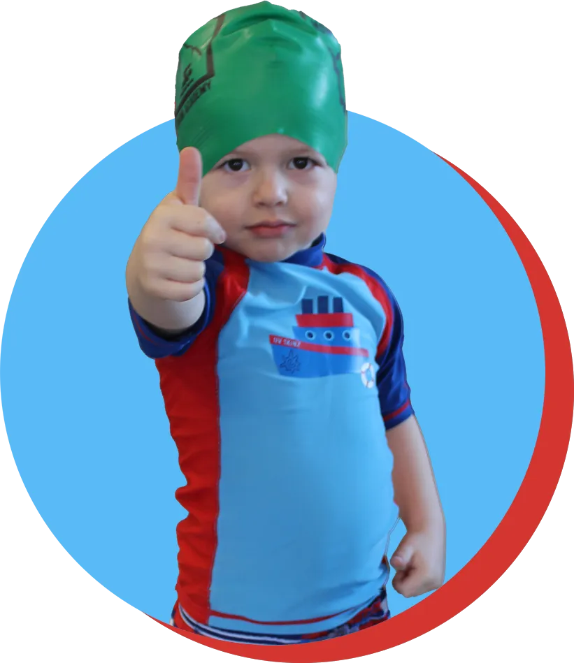 boy with green Montana. Swim Academy swim cap and swim suit and thumbs up