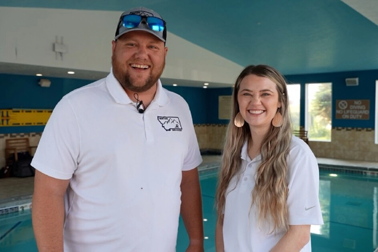 The owners of Montana Swim Academy stand in front of a hotel pool.