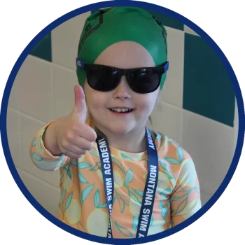 Smiling girl with thumbs up wearing swim goggles and a green Montana Swim Academy swim cap